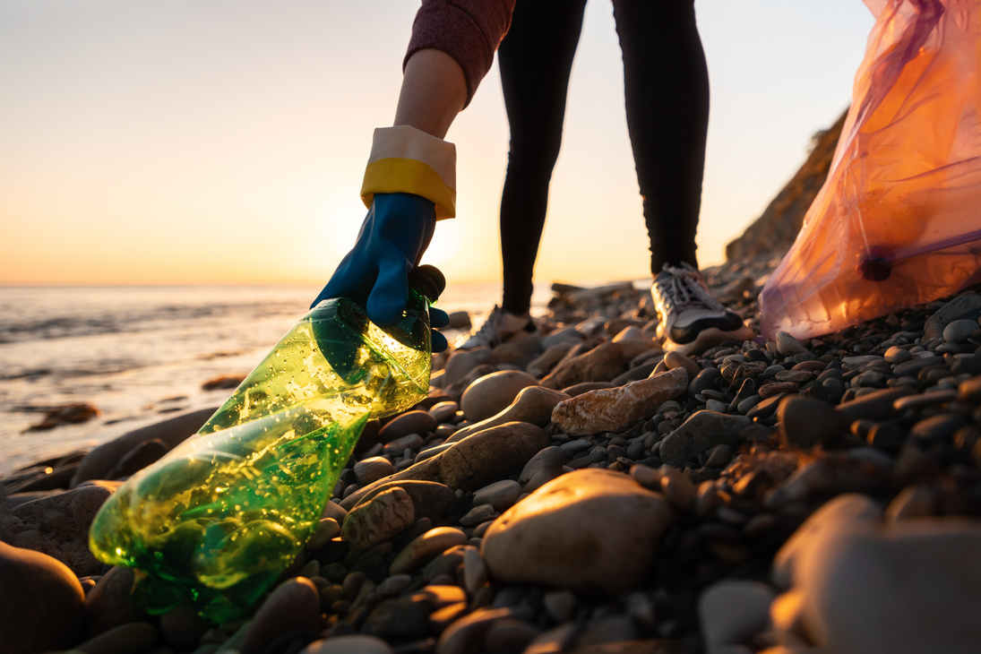 Conservation of ecology and garbage collection for recycling. A volunteer collects plastic bottles by the sea. Concept of coastal cleanup and global environmental pollution